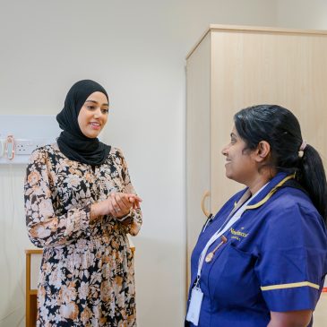 A consultant and a nurse convers in a patient's room