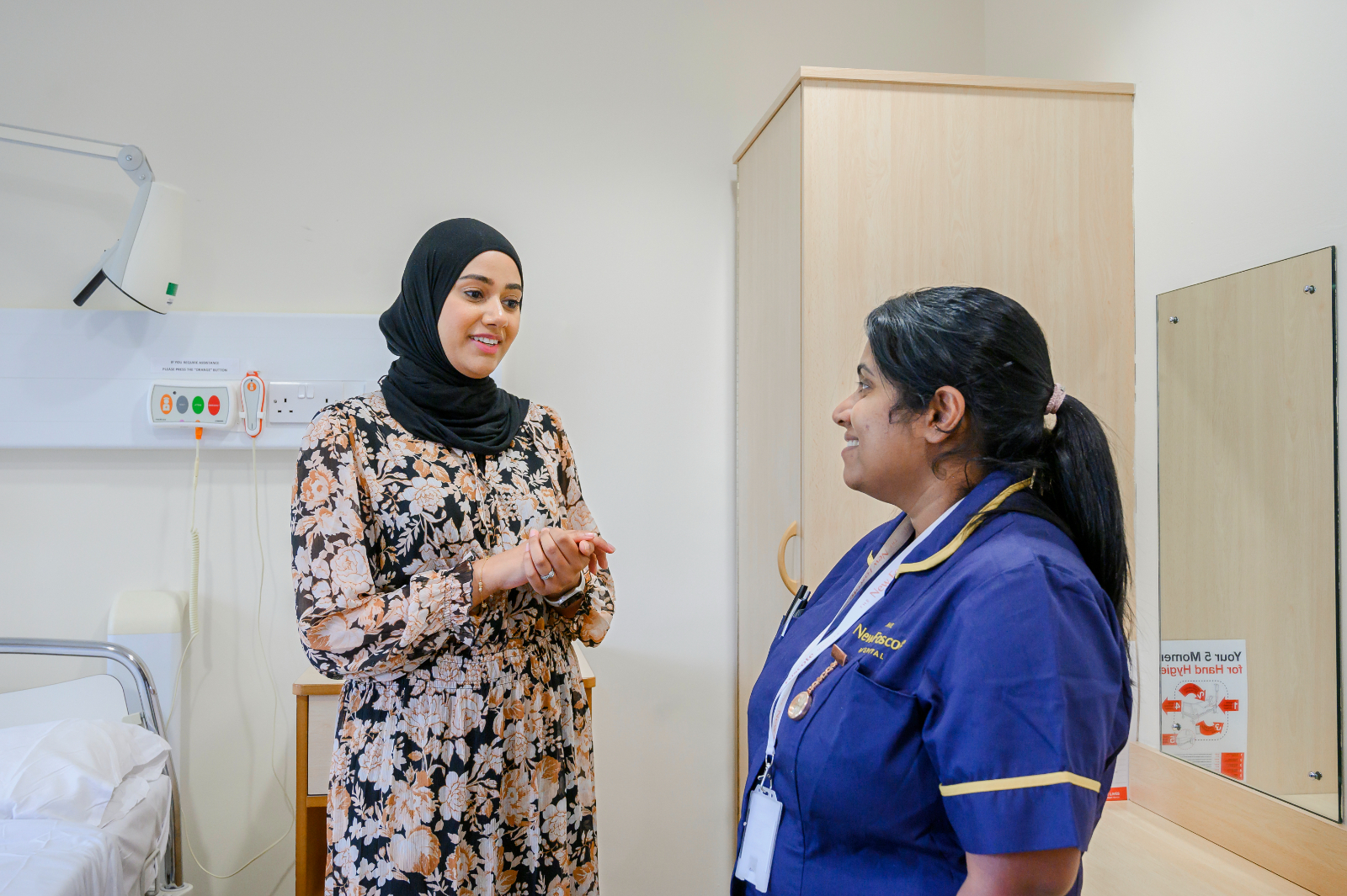 A consultant and a nurse convers in a patient's room