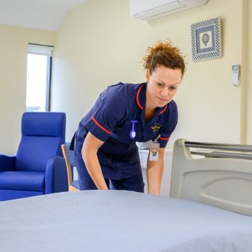 A nurse makes the bed in a private hospital room