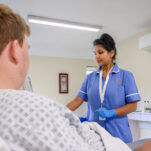 A nurse talks with a patient in their private room