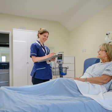 Nurse speaks with a patient in their private room